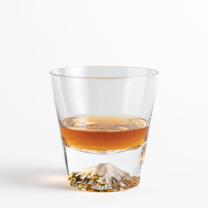 Glass with a whisky, showcasing an embossed Mount Fuji at the base, creating a striking visual effect.