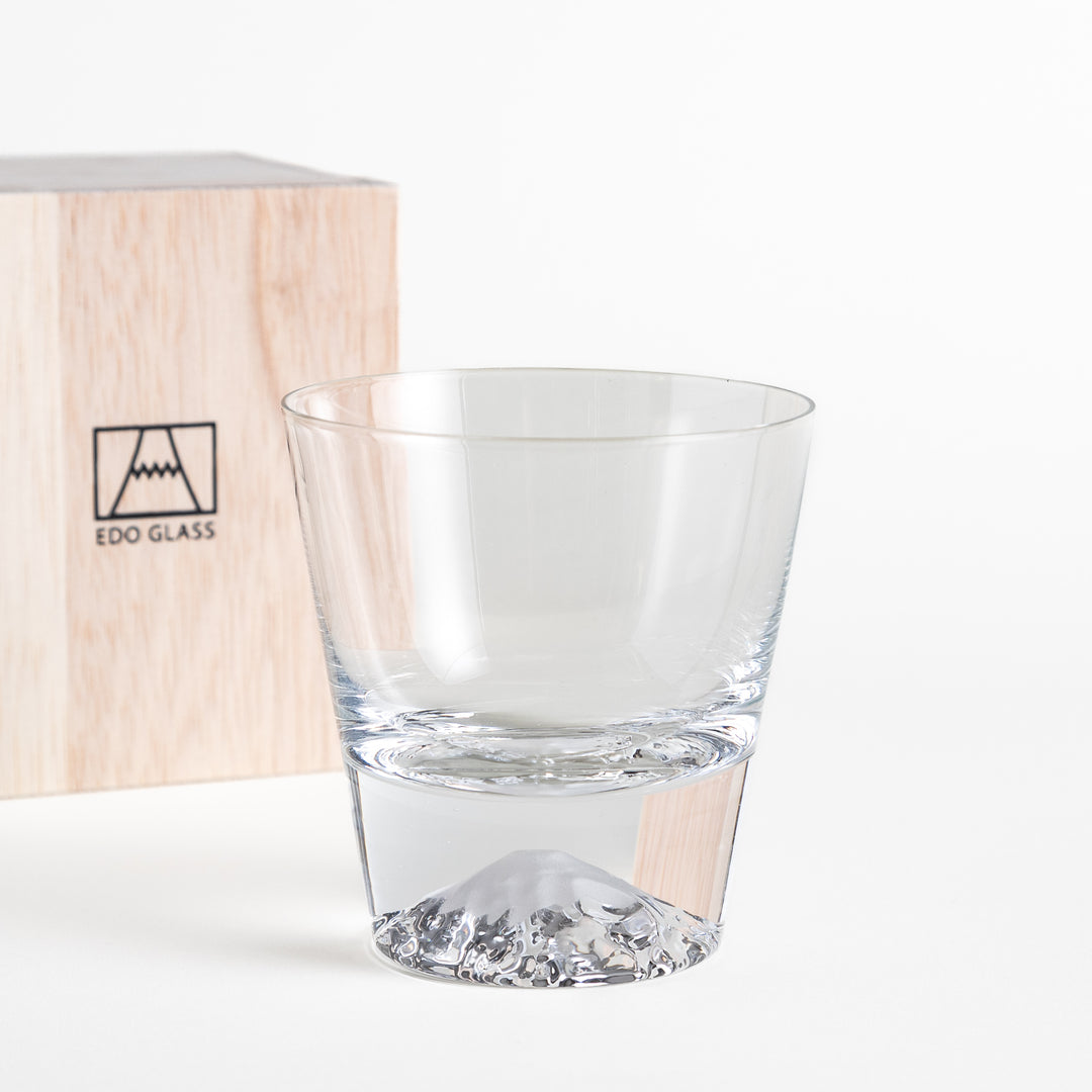 Glass with a mountain-shaped base placed next to the wooden box with the "EDO GLASS" logo. The glass features clear craftsmanship with the mountain base at the bottom.