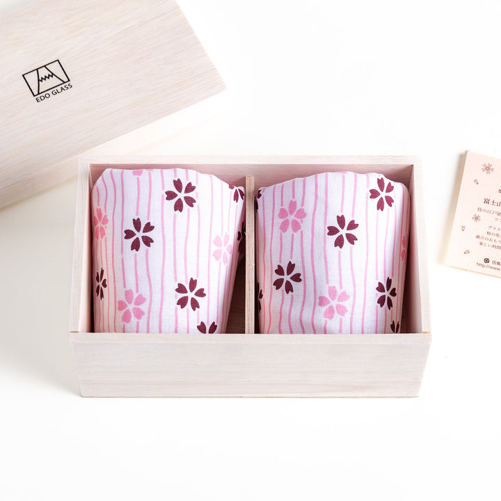 Wooden box with two glasses wrapped in pink fabric printed with cherry blossom patterns, perfect for gifting or special occasions.