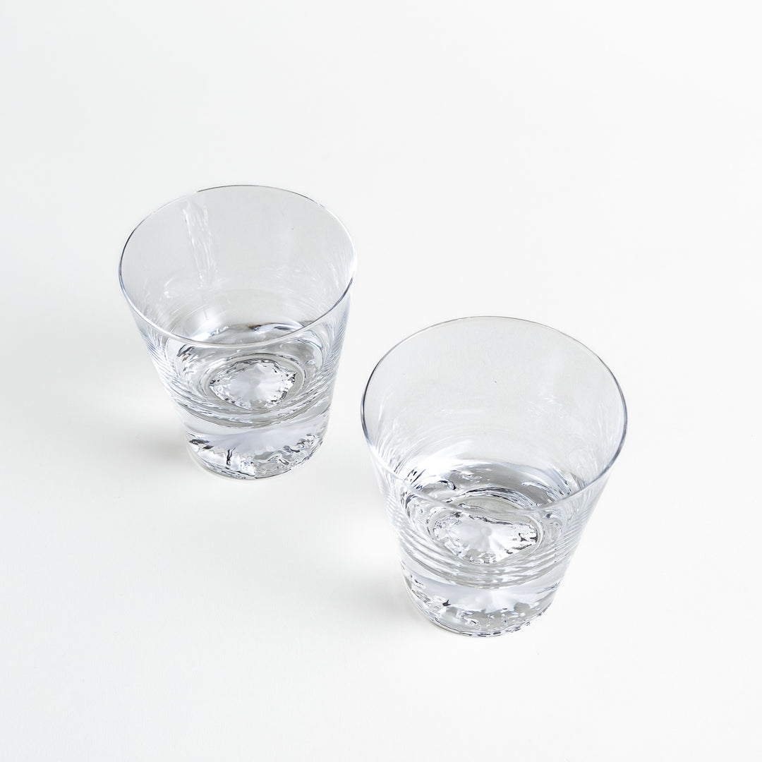 Pair of clear rocks glasses with Mt. Fuji base design, angled view showing intricate detailing and polished glass surface.