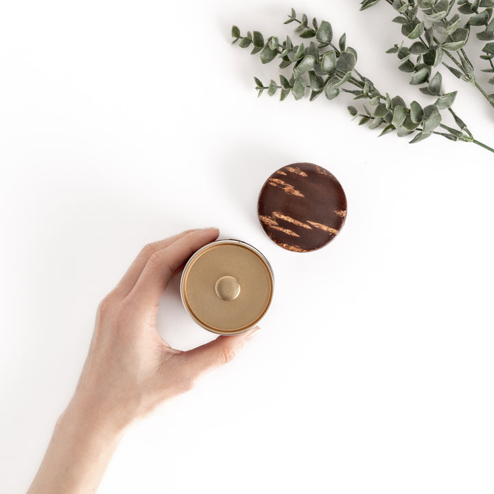 Hand holding a cherry bark tea caddy with a separate lid, revealing a golden interior, perfect for storing and preserving loose leaf tea.