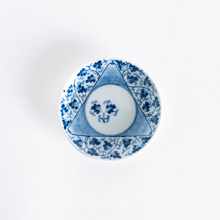 Top view of a three-sided sauce dish featuring a delicate arabesque floral pattern in blue, surrounding a central circular motif.