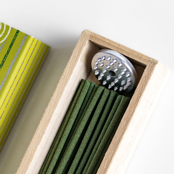 Tranquil Matcha Incense in a light wooden box with vibrant green sticks, elegantly packaged in a yellow design featuring white circular patterns, evoking the calming aroma of green tea.