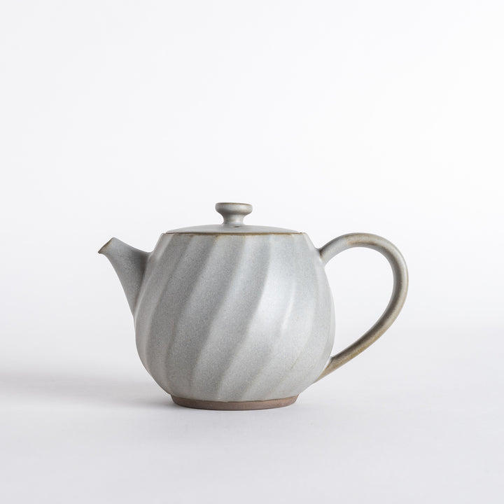 Side view highlighting the graceful shape and smooth finish of the teapot, a charming addition to any kitchen.