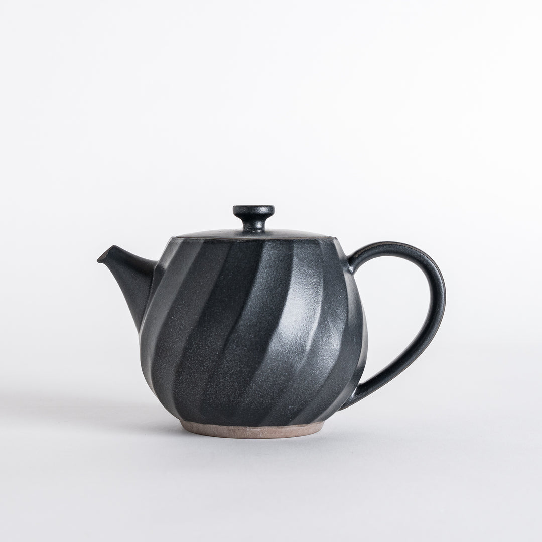 Black teapot highlighting a twisted pattern and a simple lid, combining function and elegance for tea enjoyment.