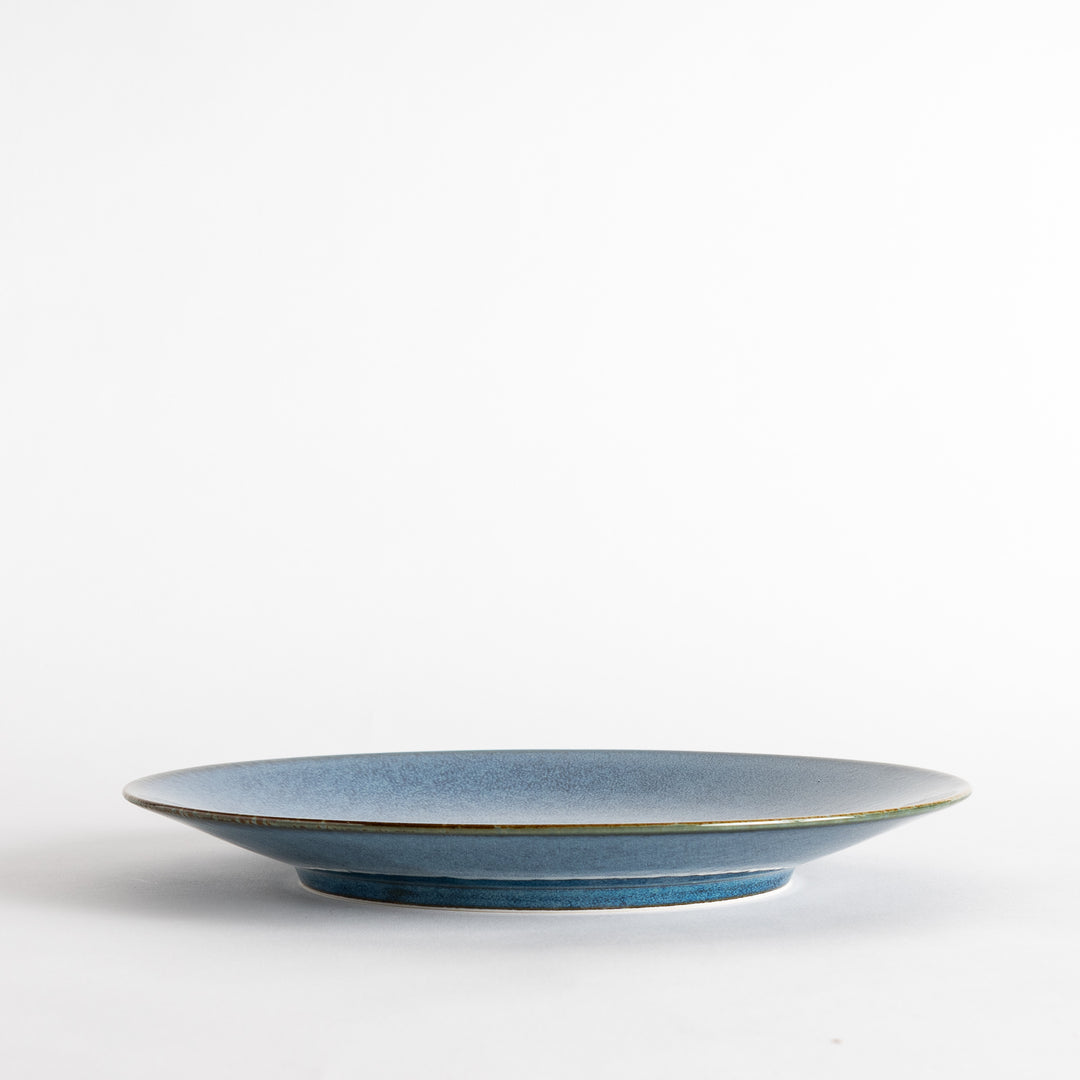 A round dinner plate with a deep blue gradient finish and a subtle textured surface.