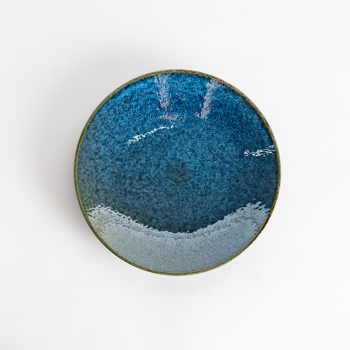 A round salad plate featuring a deep blue color and a fine speckled texture.