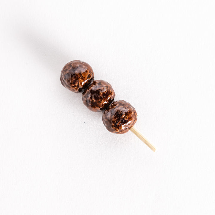 Chopsticks rest shaped like skewered tsukune chicken meatballs with a glossy brown finish.