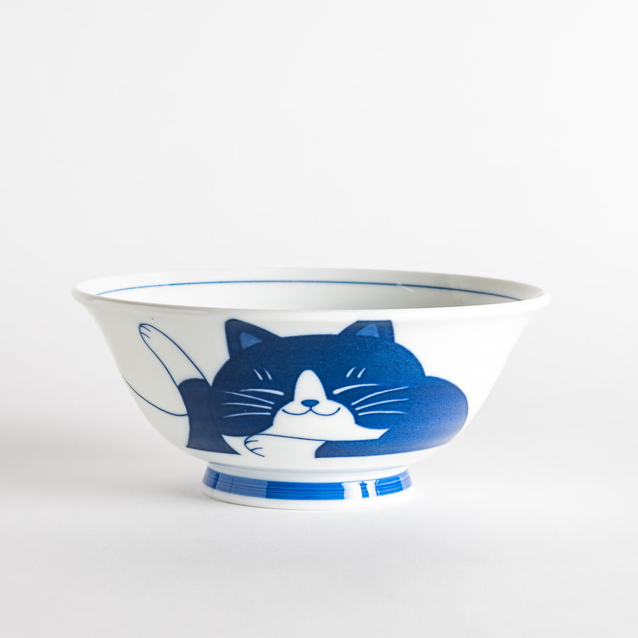 A white ramen bowl featuring a playful blue cat lying down with its eyes closed.