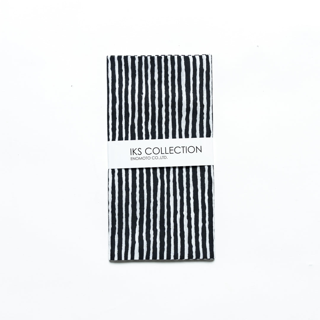 Black hand towel with vertical white stripes, folded with a product sleeve.