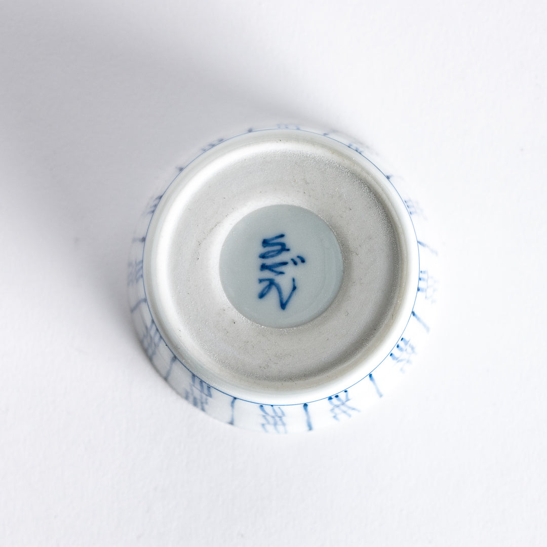 View of the underside of the blue vertical bamboo line patterned bowl, showing its plain white base.