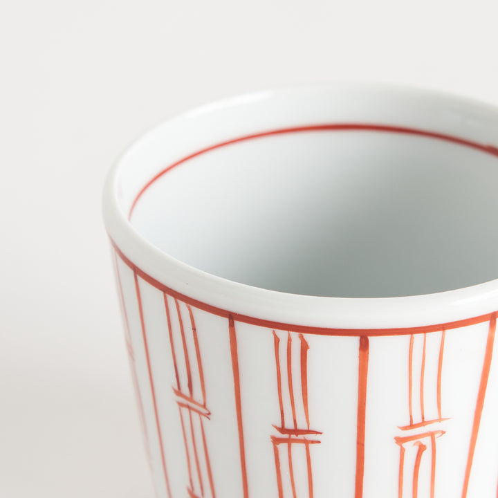 A small white porcelain bowl with vertical red lines resembling bamboos as a decorative pattern.