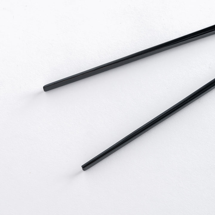 Close-up of black lacquered chopsticks, featuring smooth, straight tips and a simple design.