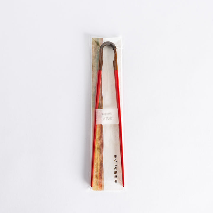 Red chopsticks in packaging, featuring the curved wooden joint and sleek red finish, packaged in a delicate and elegant presentation.