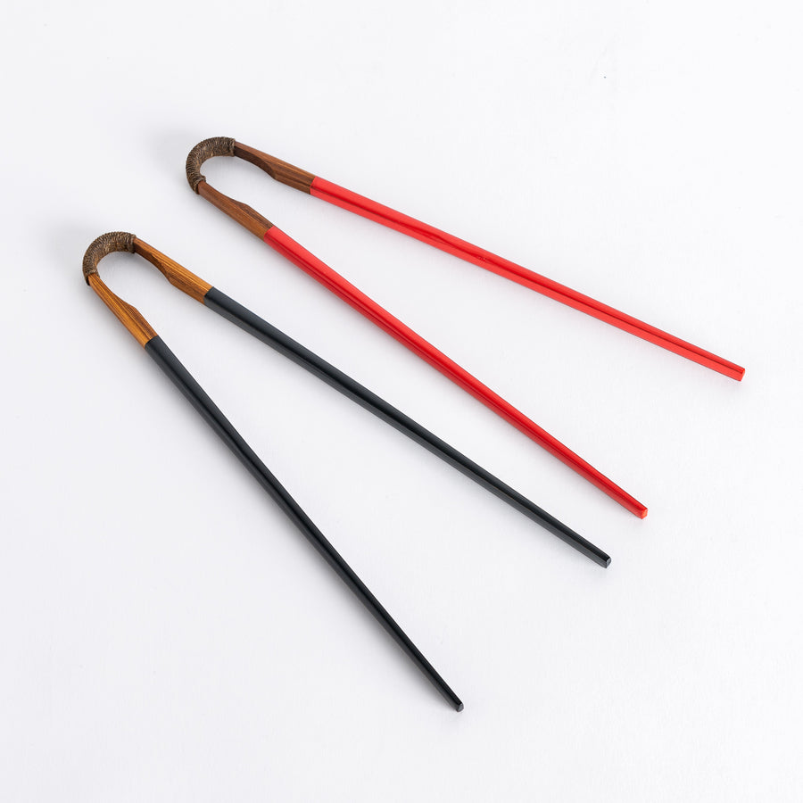 Vintage chopsticks with black and red lacquered tips, featuring a curved wooden handle wrapped in twine.