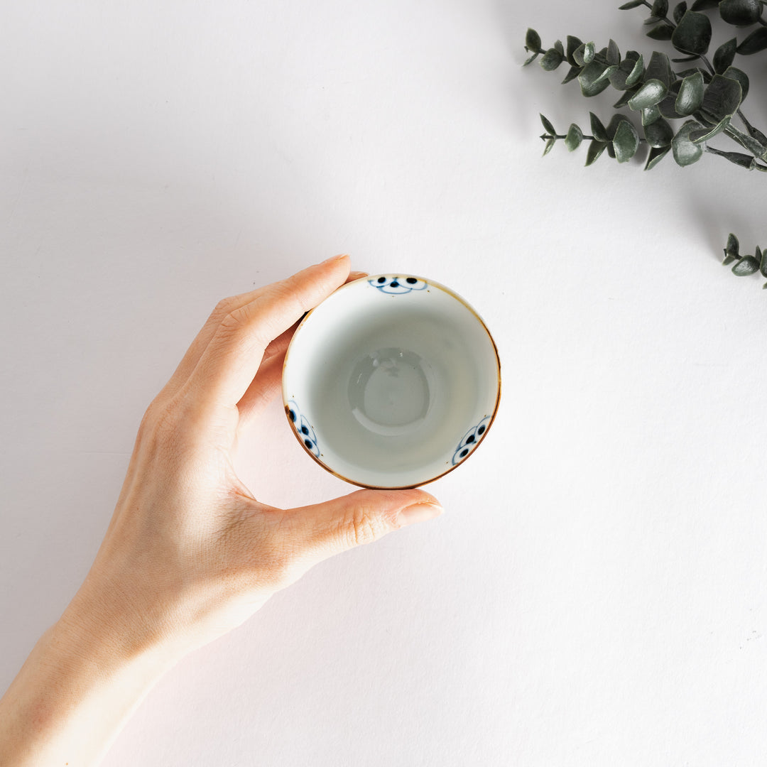 Teacup held in hand, displaying the beautiful blue floral design and elegant shape for a comfortable grip.