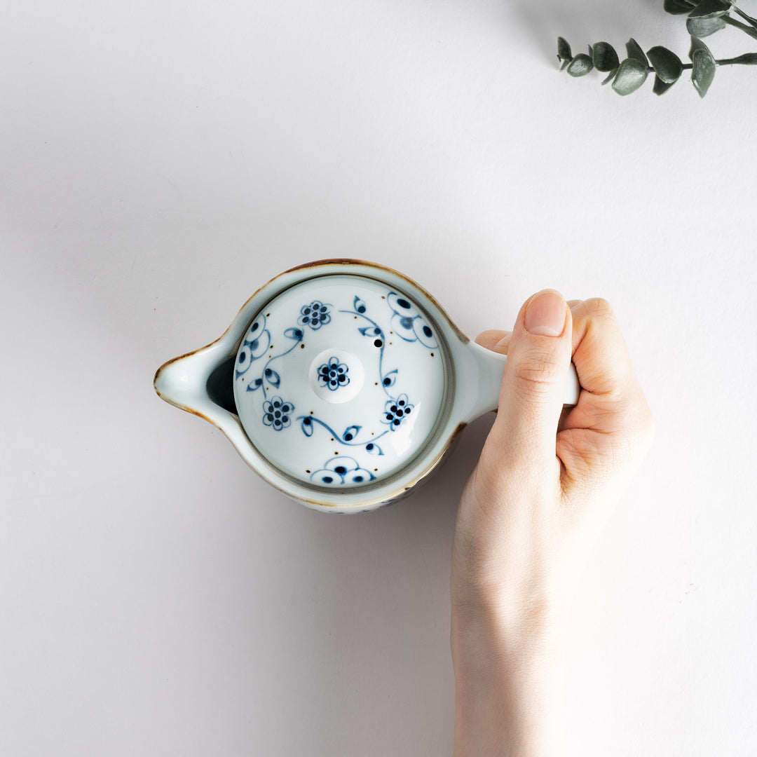 Close-up of the teapot held in hand, showcasing intricate floral design and elegant handle for size and refined style.