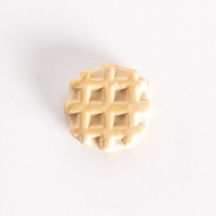 A waffle-shaped ceramic chopsticks rest with a textured, golden-brown grid design.