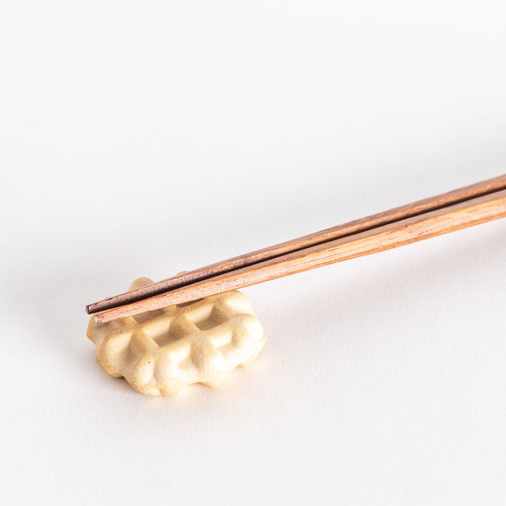 Close-up of a waffle-shaped chopsticks rest with chopsticks gently placed on top.