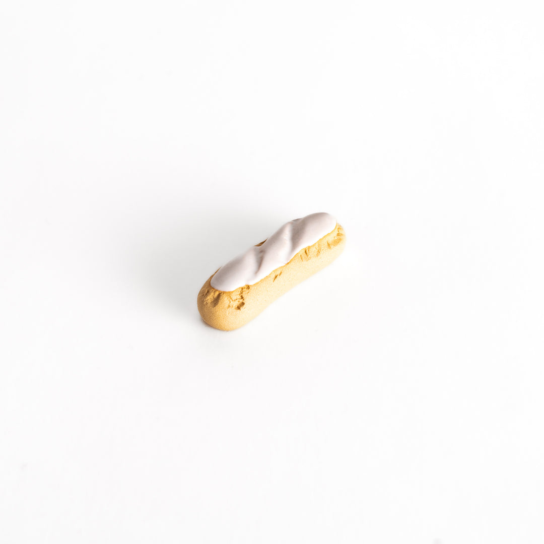 White chocolate éclair-shaped chopsticks rest with a golden-brown base and glossy white chocolate topping, featuring a realistic and elegant design.