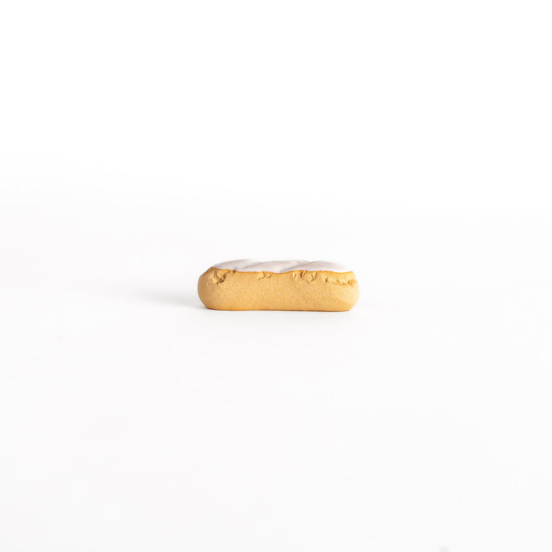 Side view of the white chocolate éclair-shaped chopsticks rest, capturing its elongated shape and delicate white chocolate detailing.