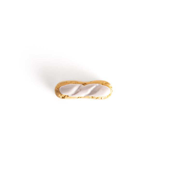 Top view of the white chocolate éclair-shaped chopsticks rest, emphasizing its glossy white topping and intricate golden-brown base.