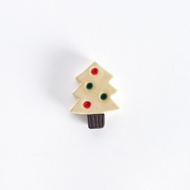 A ceramic chopsticks rest shaped like a white Christmas tree with red and green ornaments.