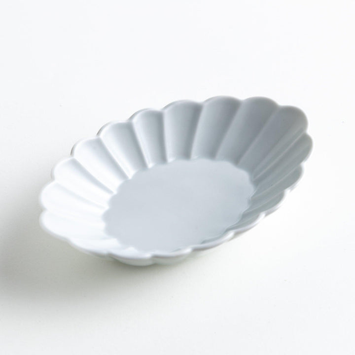 A white porcelain oval dessert bowl with a scalloped design.