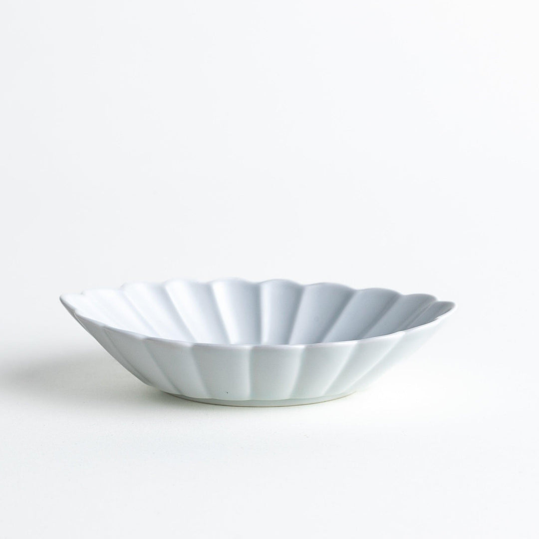 A white porcelain oval dessert bowl with a scalloped design.