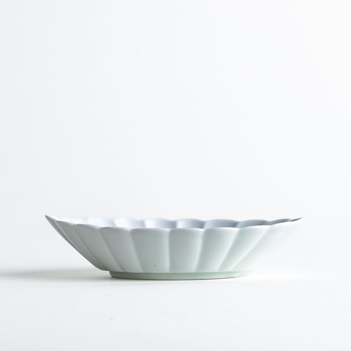 A white porcelain oval dessert bowl with a scalloped design.