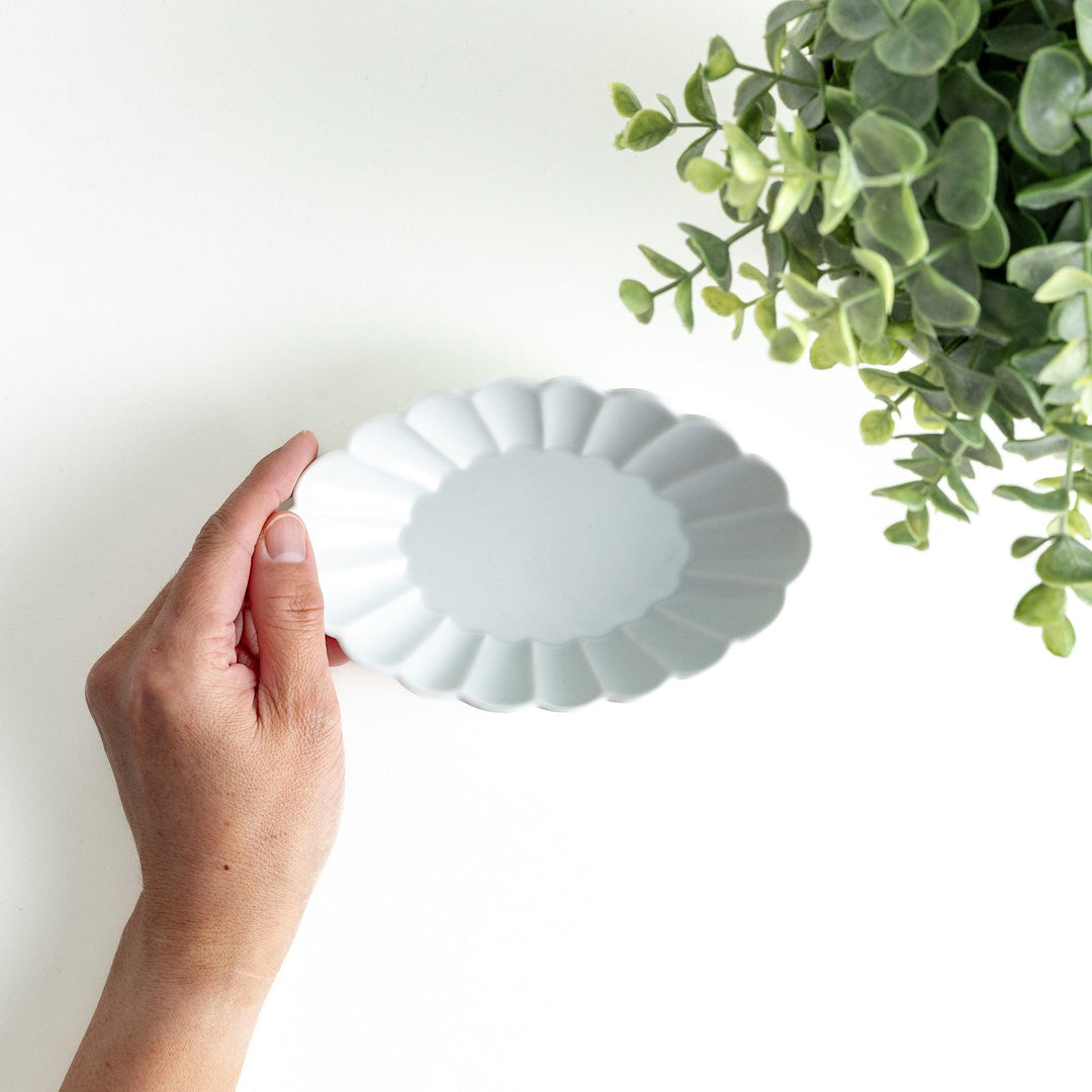 A white porcelain oval dessert bowl with a scalloped design.