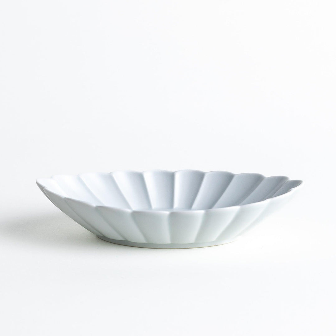 A white porcelain oval pasta bowl with a scalloped design.