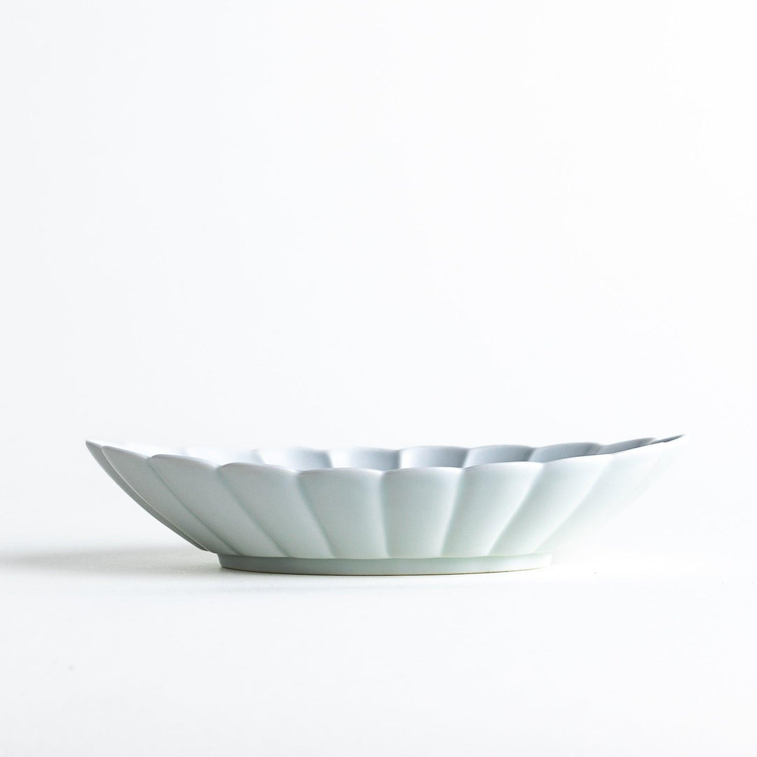 A white porcelain oval pasta bowl with a scalloped design.