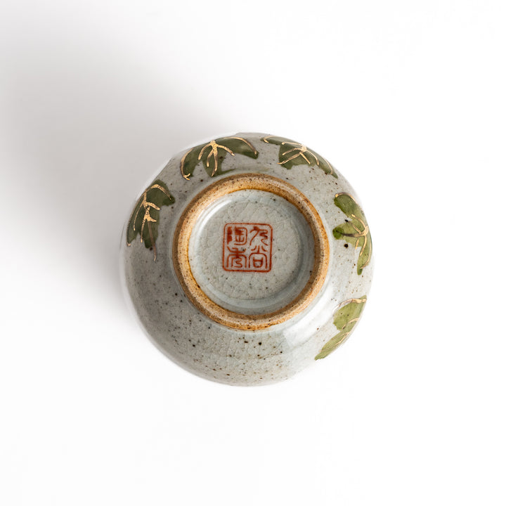 Ceramic teacup with a delicate white flower design and green leaves, perfect for enjoying a peaceful moment with tea.