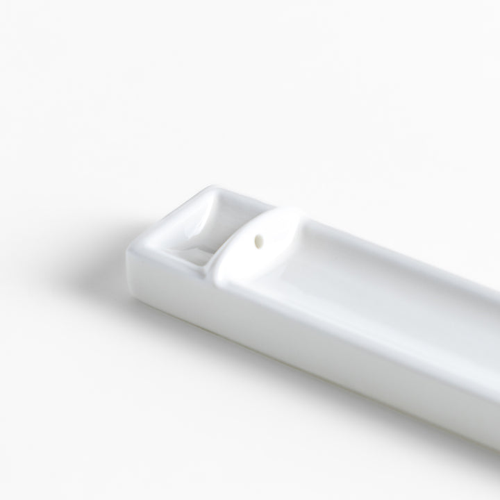 Incense Holder in a minimalist white ceramic design with a built-in slot for holding sticks, featuring a rectangular shape that neatly catches falling ash for a clean display.