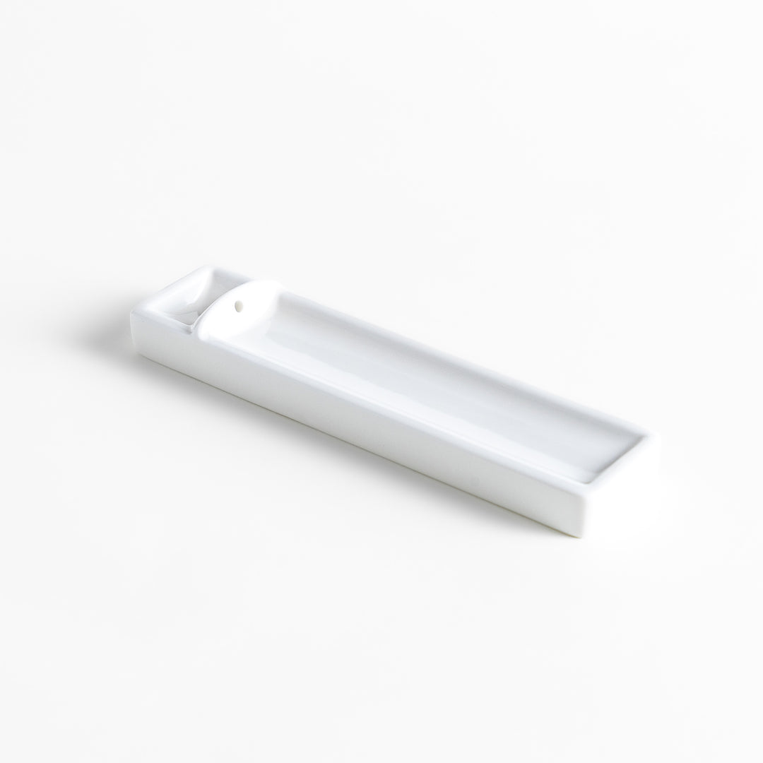 Incense Holder in a minimalist white ceramic design with a built-in slot for holding sticks, featuring a rectangular shape that neatly catches falling ash for a clean display.