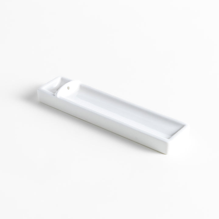 Incense Holder in a minimalist white ceramic design with a built-in slot for holding sticks, featuring a rectangular shape that neatly catches falling ash for a clean display.