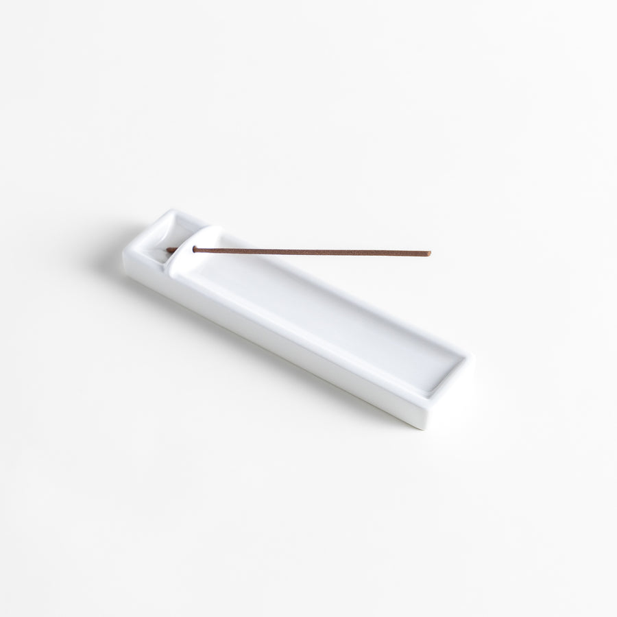 Incense Holder in a minimalist white ceramic design with a built-in slot for holding sticks, featuring a rectangular shape that neatly catches falling ash for a clean display.