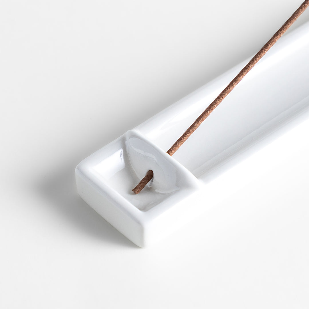 Incense Holder in a minimalist white ceramic design with a built-in slot for holding sticks, featuring a rectangular shape that neatly catches falling ash for a clean display.