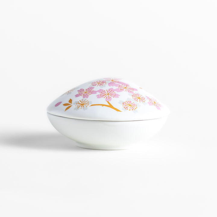 White ceramic incense holder shaped like a seashell, adorned with delicate pink and gold cherry blossoms, featuring a sakura-shaped holder for a refined touch.