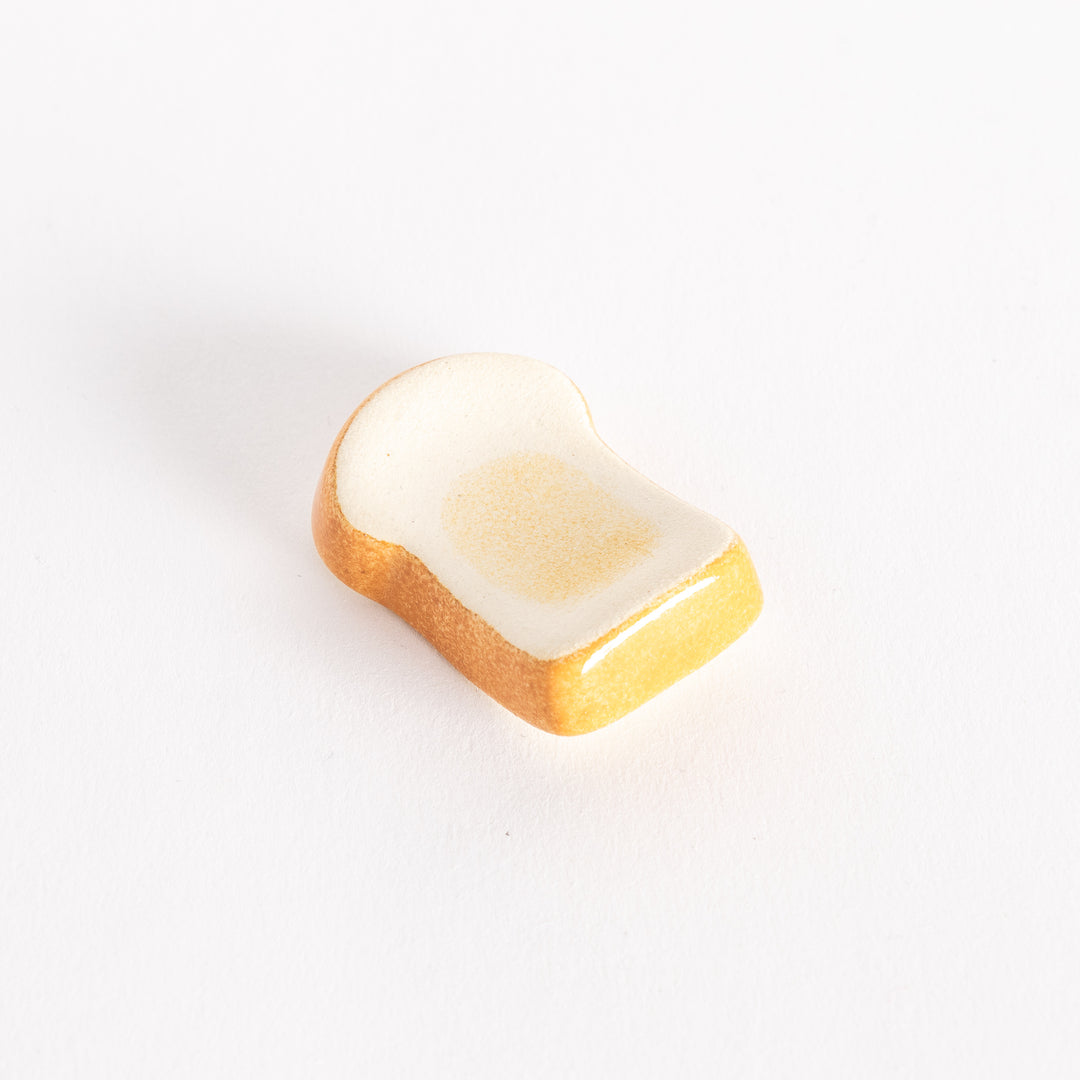 Toast-shaped chopsticks rest shown from a slight angle, highlighting its toasted details and textured surface.