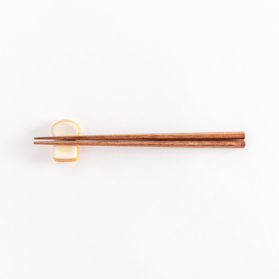 The toast-shaped chopsticks rest with chopsticks on top, photographed from a distance.