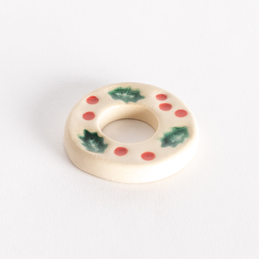 A slightly angled view of the ceramic wreath chopstick rest, showcasing its circular shape and detailed holiday-themed decorations.