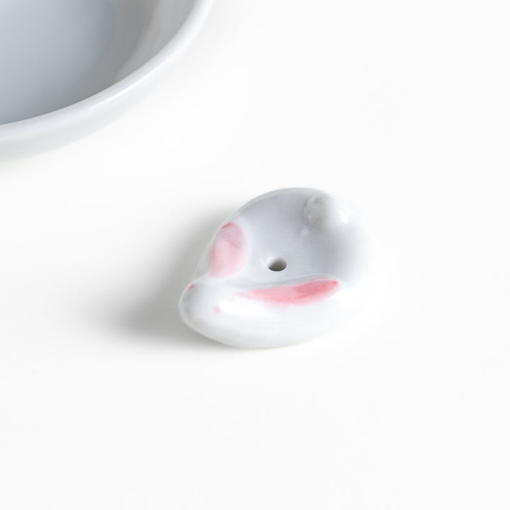 White ceramic incense holder set featuring a round dish and a rabbit-shaped holder with pink accents, designed to catch ash neatly while adding a charming touch.