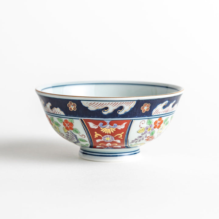 A porcelain bowl adorned with traditional Japanese motifs, including floral and geometric designs in blue, red, and green with gold accents.