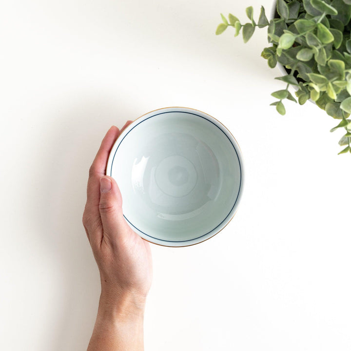 A porcelain bowl adorned with traditional Japanese motifs, including floral and geometric designs in blue, red, and green with gold accents.