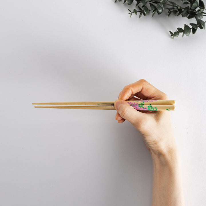 Hand holding chopsticks with bamboo design, demonstrating their elegant appearance and fine craftsmanship.