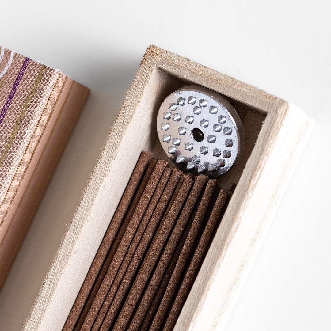 Woodland Palo Santo Incense in a light wooden box with warm brown sticks, elegantly packaged in a soft beige design featuring white circular patterns, evoking a calming and purifying Palo Santo aroma.