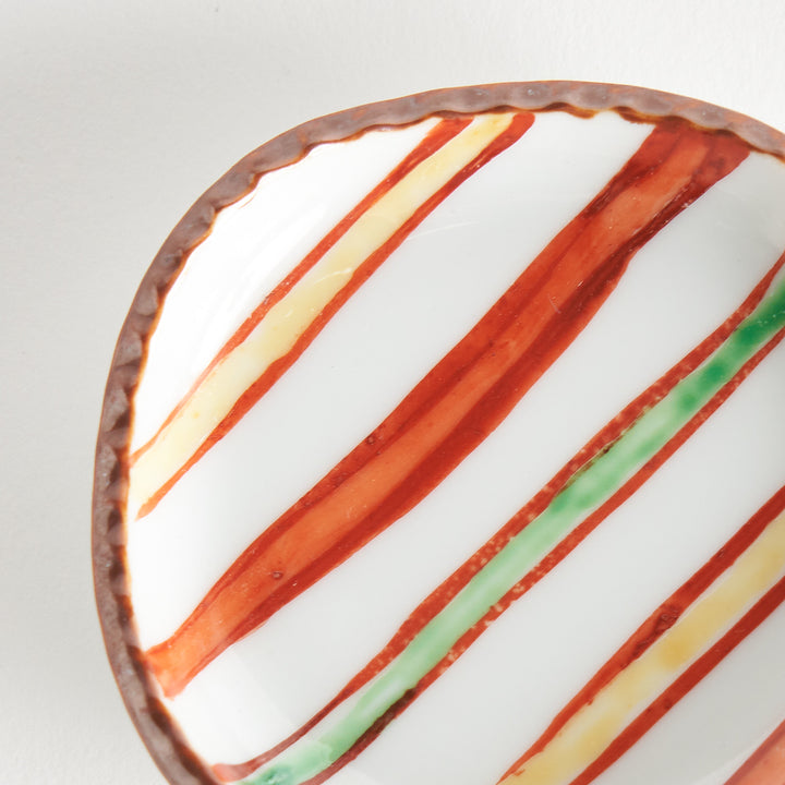 Close-up of the textured rim and colorful striped pattern of the sauce dish, capturing the details of its design.