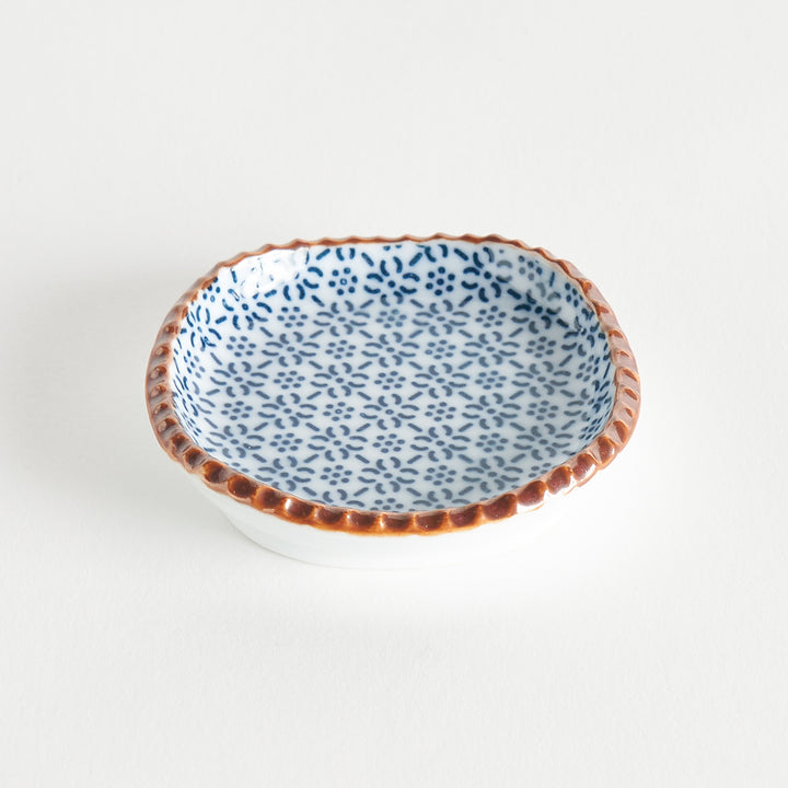 A round plate featuring a blue dotted geometric pattern with a textured brown rim.